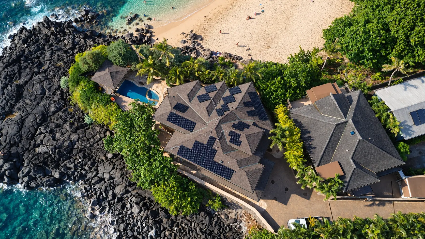 Aerial drone view of an oceanfront Oahu estate beside a sandy beach