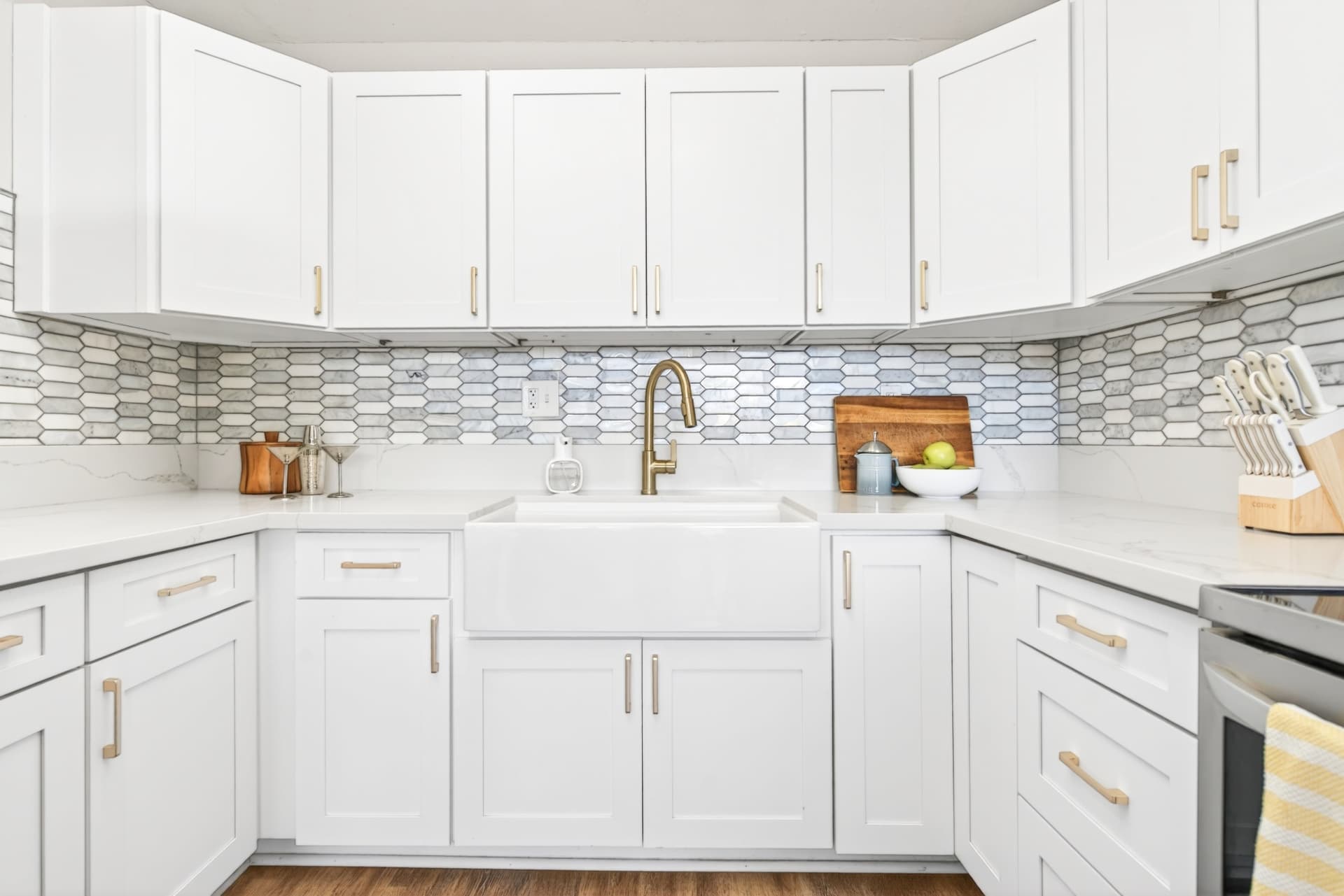 Bright white kitchen with gold fixtures and a geometric tile backsplash