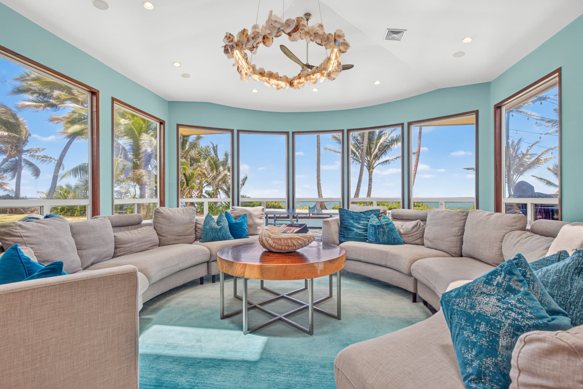 Professionally edited oceanfront Oahu living room with bright turquoise walls and clear window views