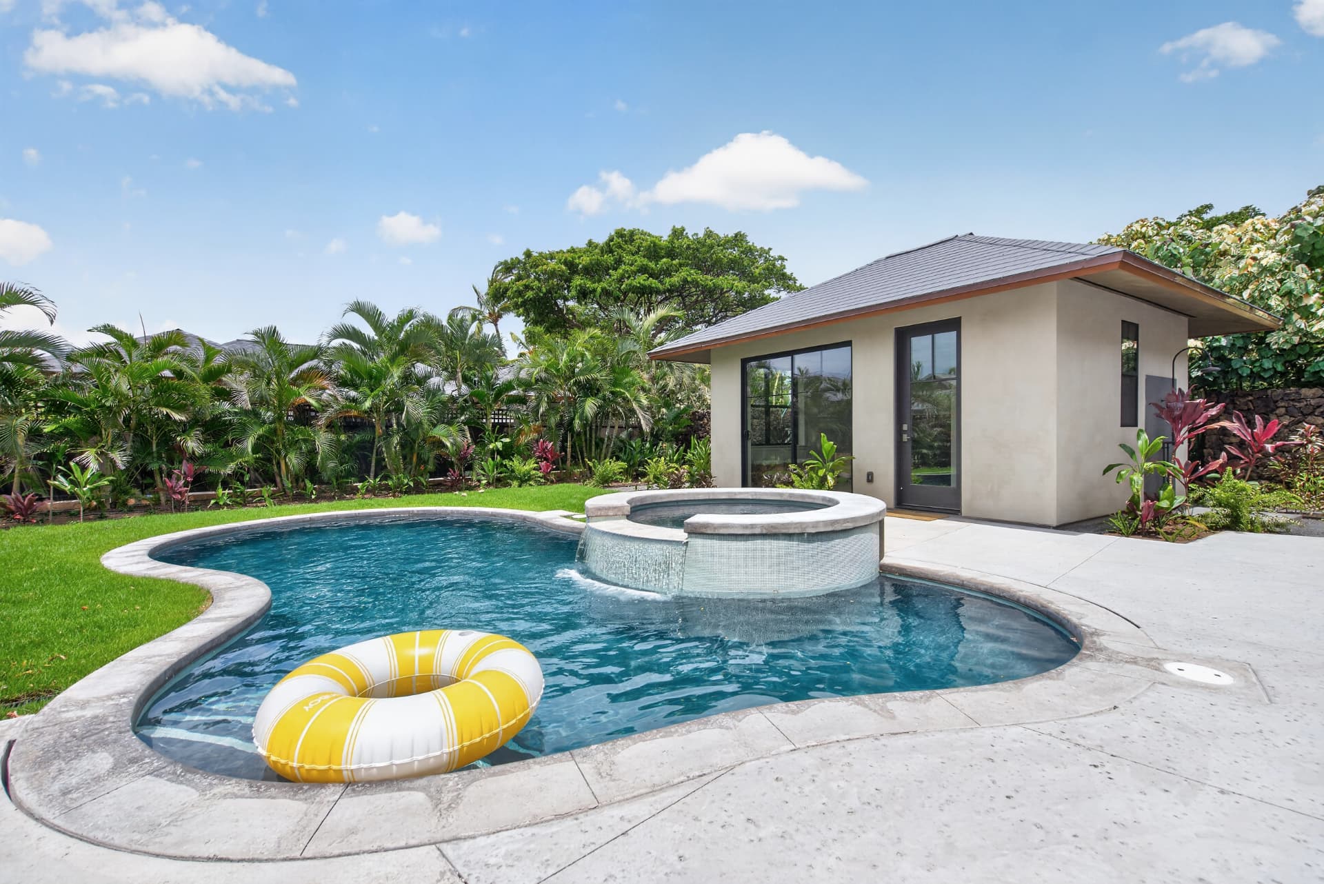 Oahu backyard swimming pool and spa surrounded by tropical landscaping