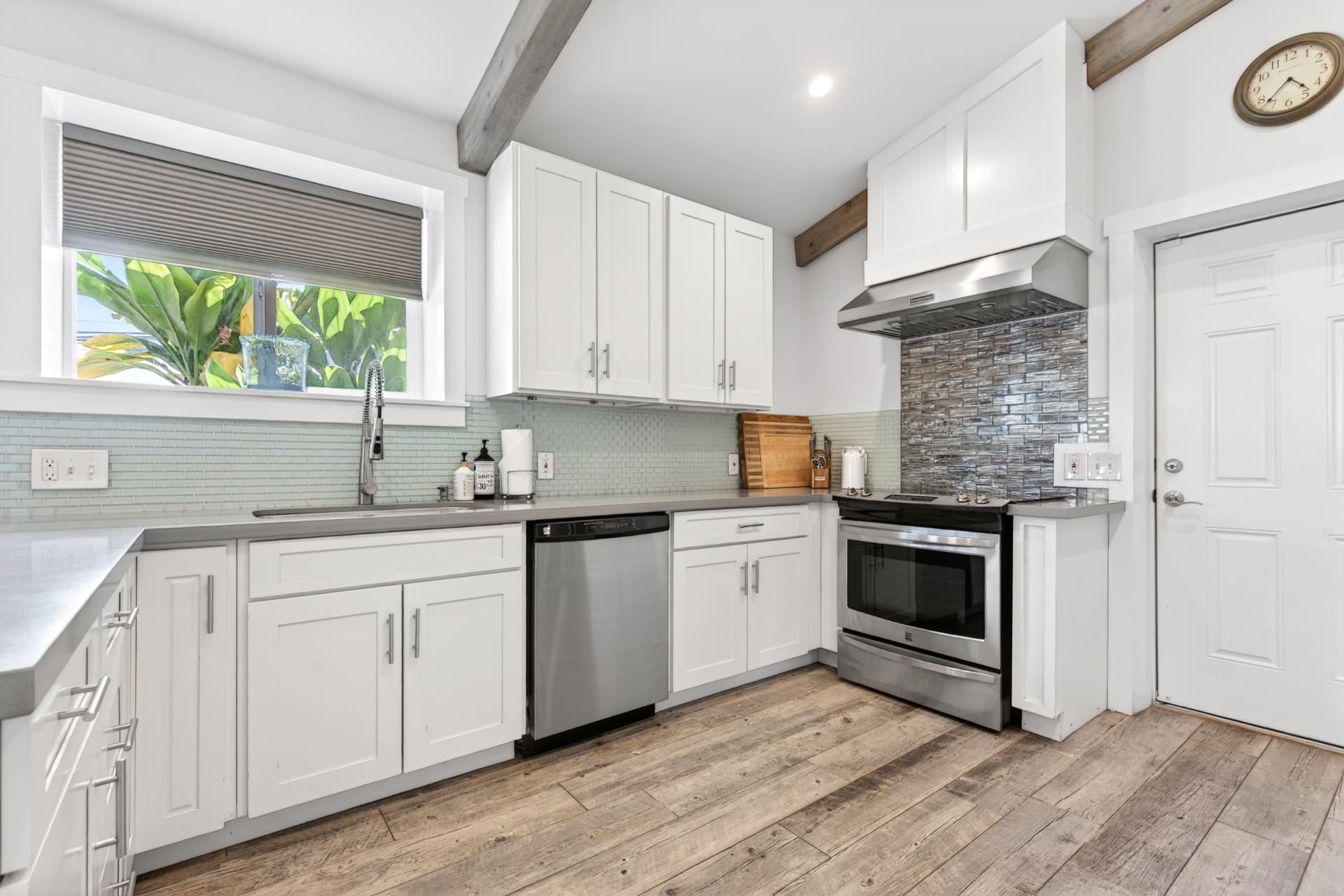 Clean white Oahu kitchen with stainless steel appliances and wood floors