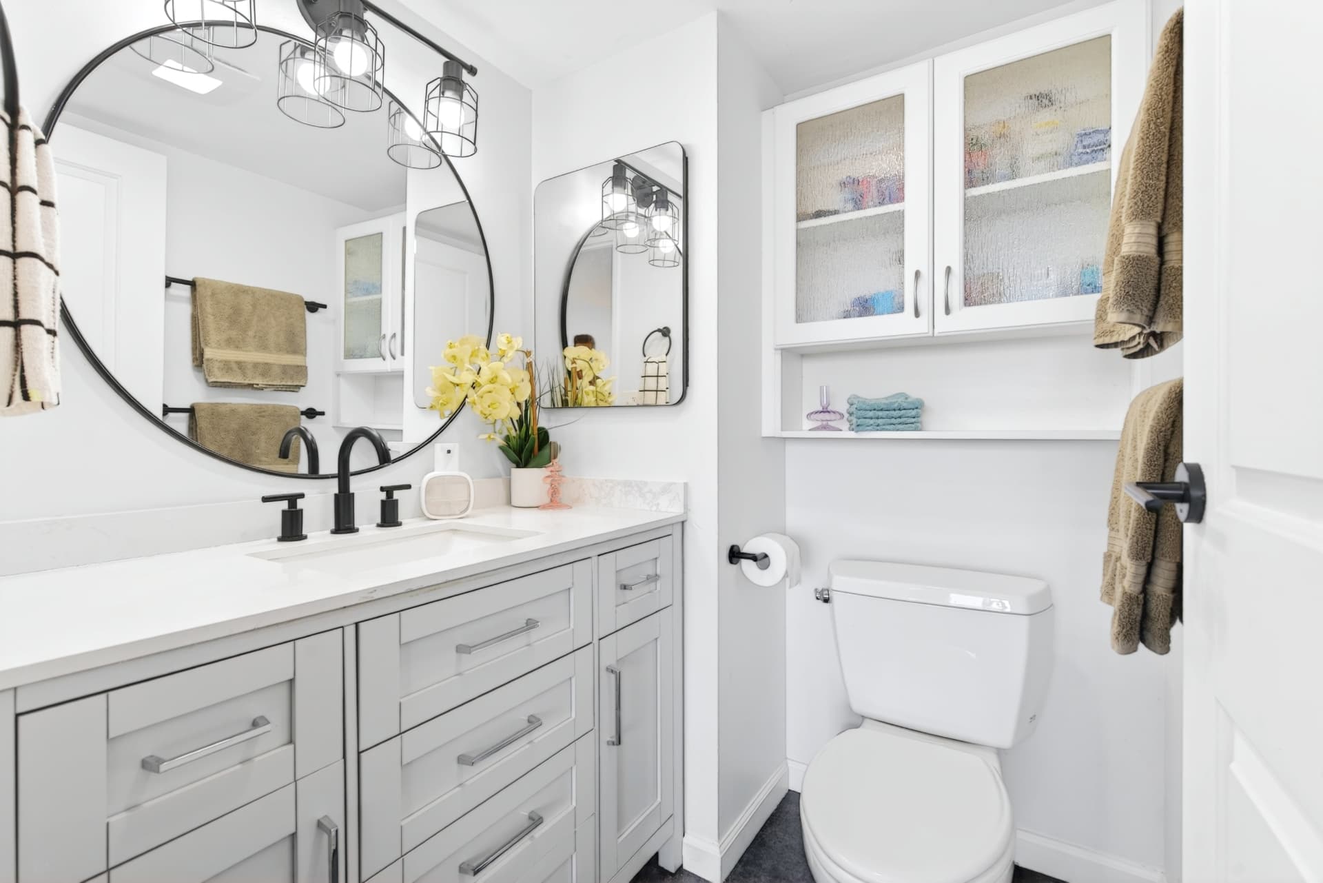 Bright modern bathroom with custom cabinetry and round statement mirror